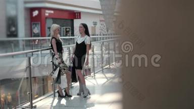 两个穿着时尚服装的女孩带着袋子在购物中心散步的腿，让穿高跟鞋的女孩靠近